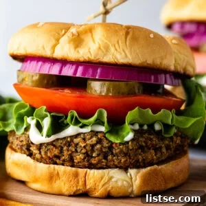veggie burgers on a sesame seed bun with lettuce, tomato, pickles ,and red onion on it