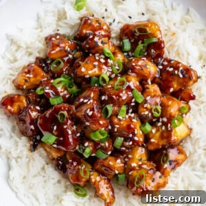 sesame tofu on a bed of white rice and topped with sesame seeds and green onion