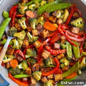 tofu stir fry in a large skillet with sesame seeds sprinkled on top