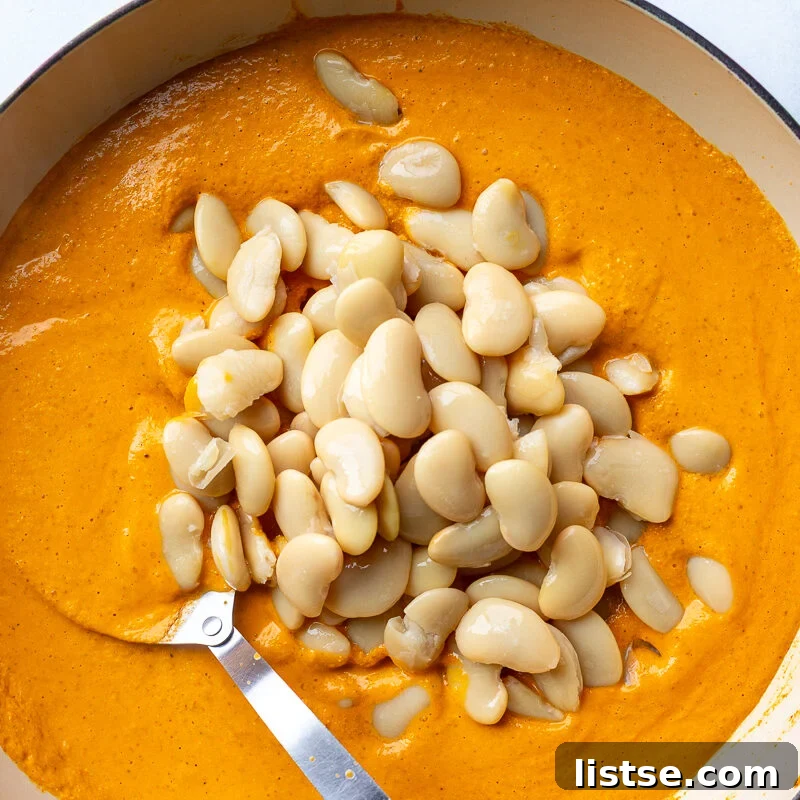 romesco sauce in a skillet with beans poured on top before theyve been stirred in