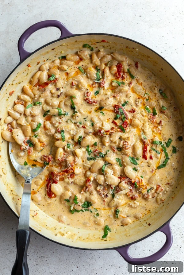 large skillet with creamy butter beans and sundried tomates