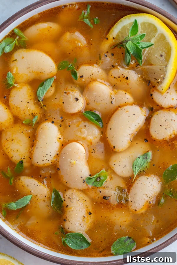brothy beans in a large bowl with lemon and fresh herbs