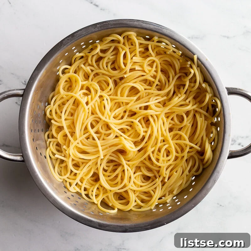 Classic Pasta Puttanesca Recipe with Anchovies and Olives 8 Cooked spaghetti draining in a colander.
