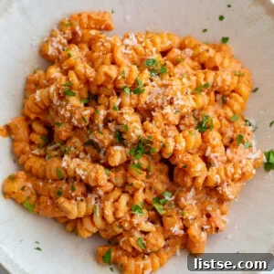 creamy tomato protein pasta in a pasta bowl and topped with herbs