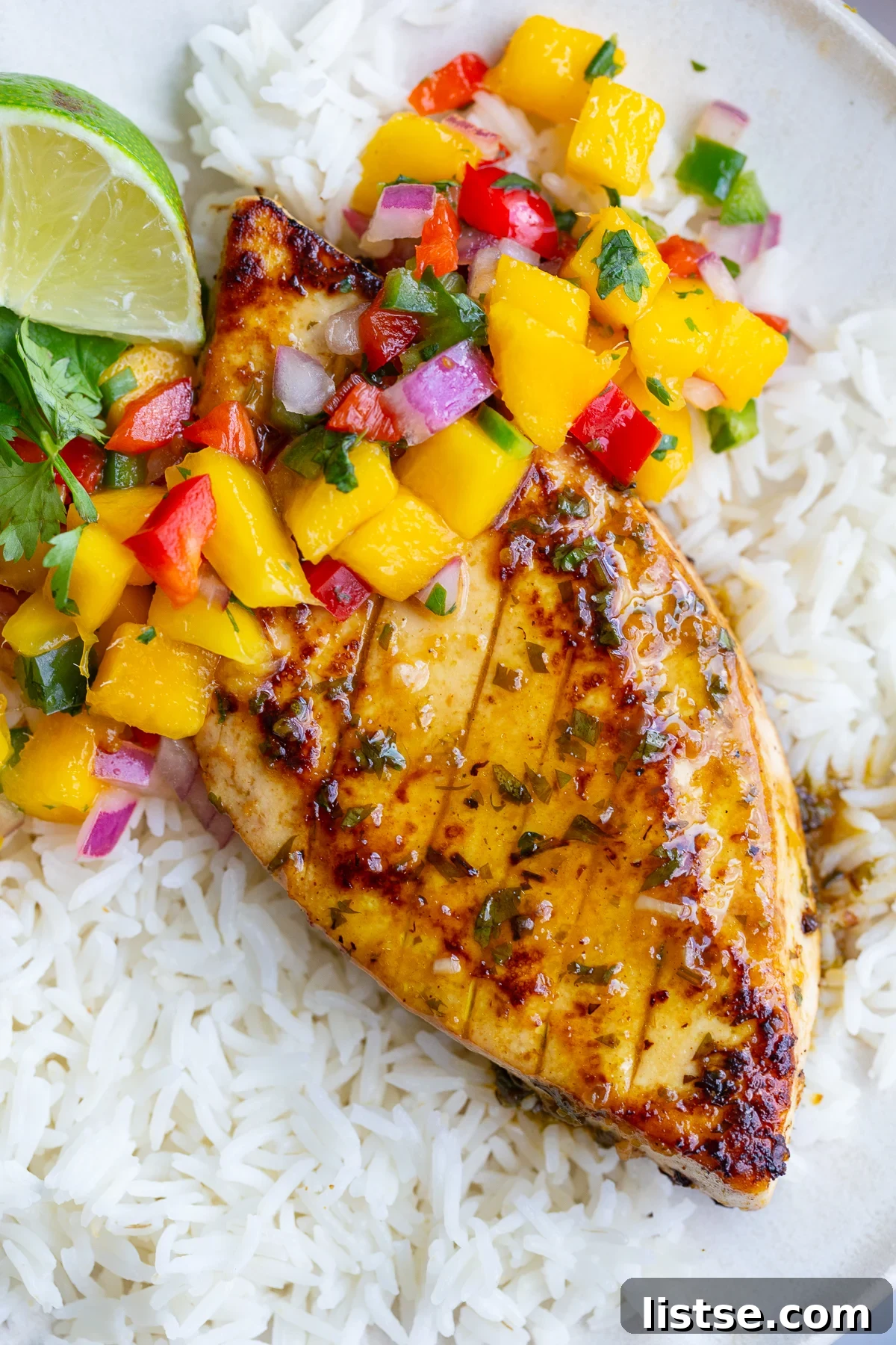 Cilantro-Lime Tofu with Fresh Mango Salsa 2 cilantro lime tofu that looks like grilled chicken with a mango salsa on top. all on a bed of rice