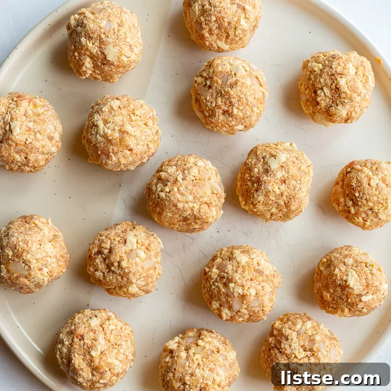 Crispy Vegan Tofu Meatballs: High-Protein Recipe 8 Rolled tofu meatballs arranged on a plate before cooking.