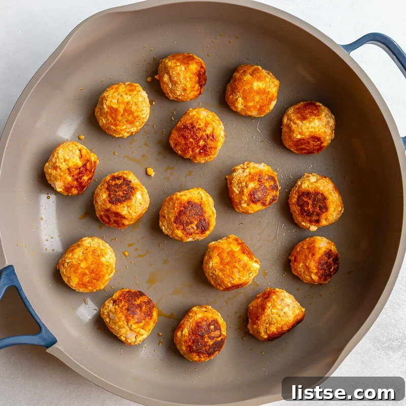 Crispy Vegan Tofu Meatballs: High-Protein Recipe 9 Tofu meatballs searing in a skillet until golden brown on several sides.