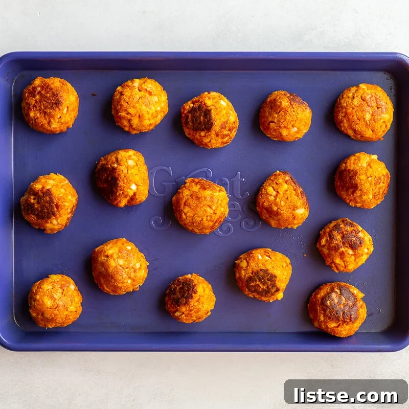 Crispy Vegan Tofu Meatballs: High-Protein Recipe 10 Tofu meatballs on a baking sheet after being baked until golden and firm.