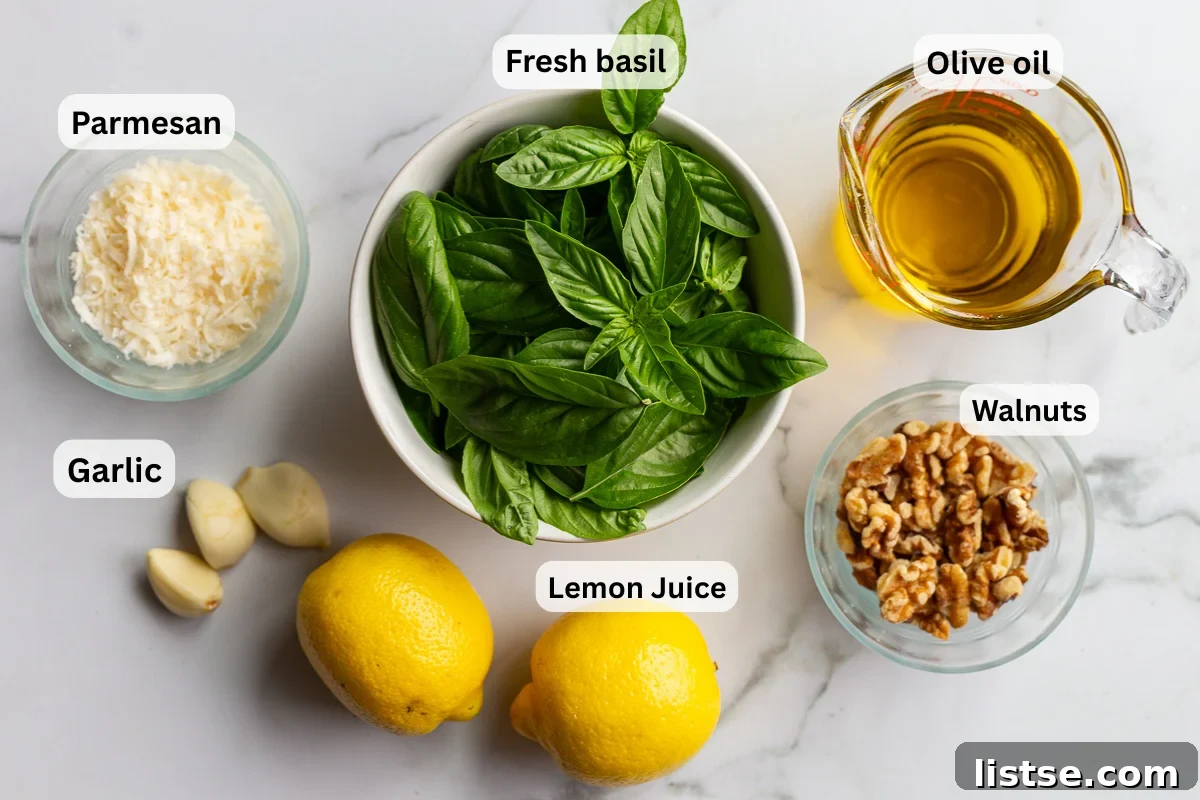 Homemade Walnut Pesto Recipe 4 Overhead shot of walnut pesto ingredients labeled on a marble counter, including fresh basil, parmesan cheese, walnuts, garlic cloves, lemons, and olive oil