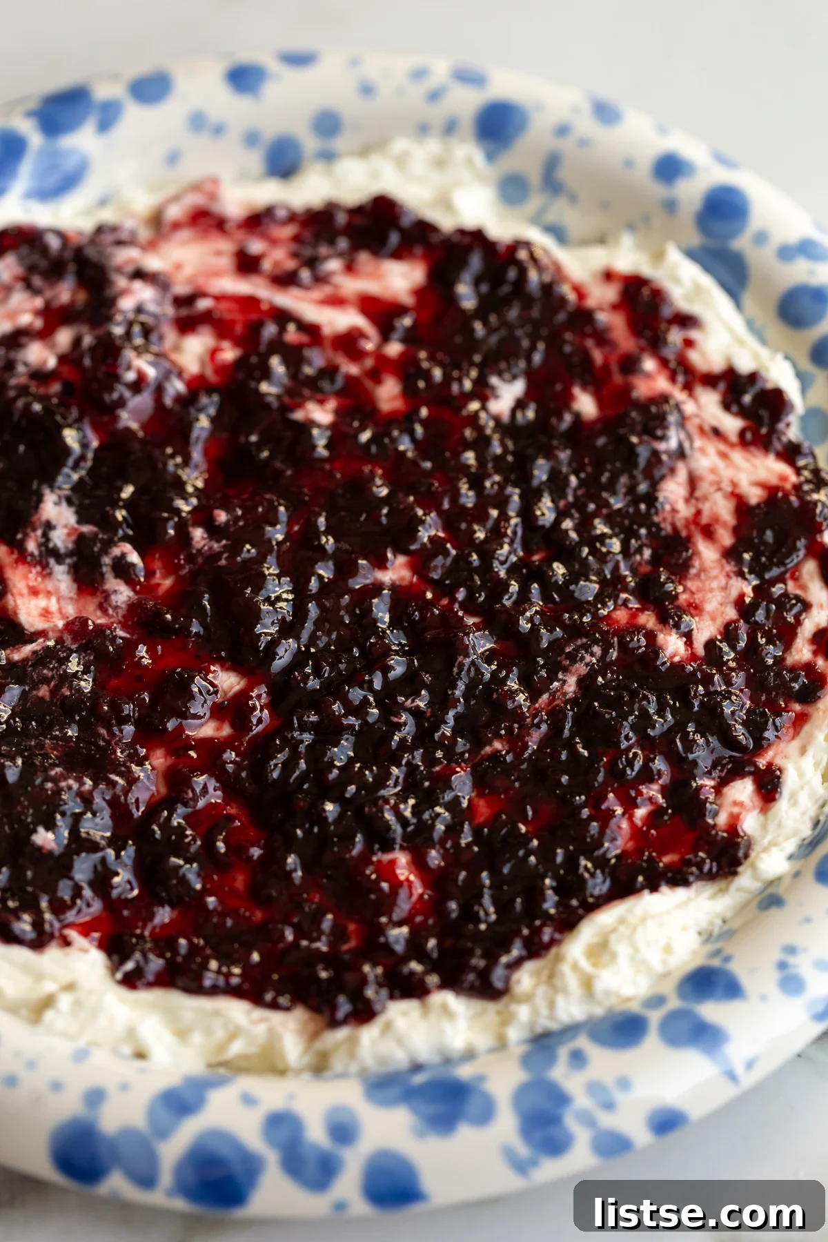 Two-Ingredient Pepper Jelly Cream Cheese Dip 2 up close shot of cream cheese and pepper jelly dip on a blue and white speckled plate
