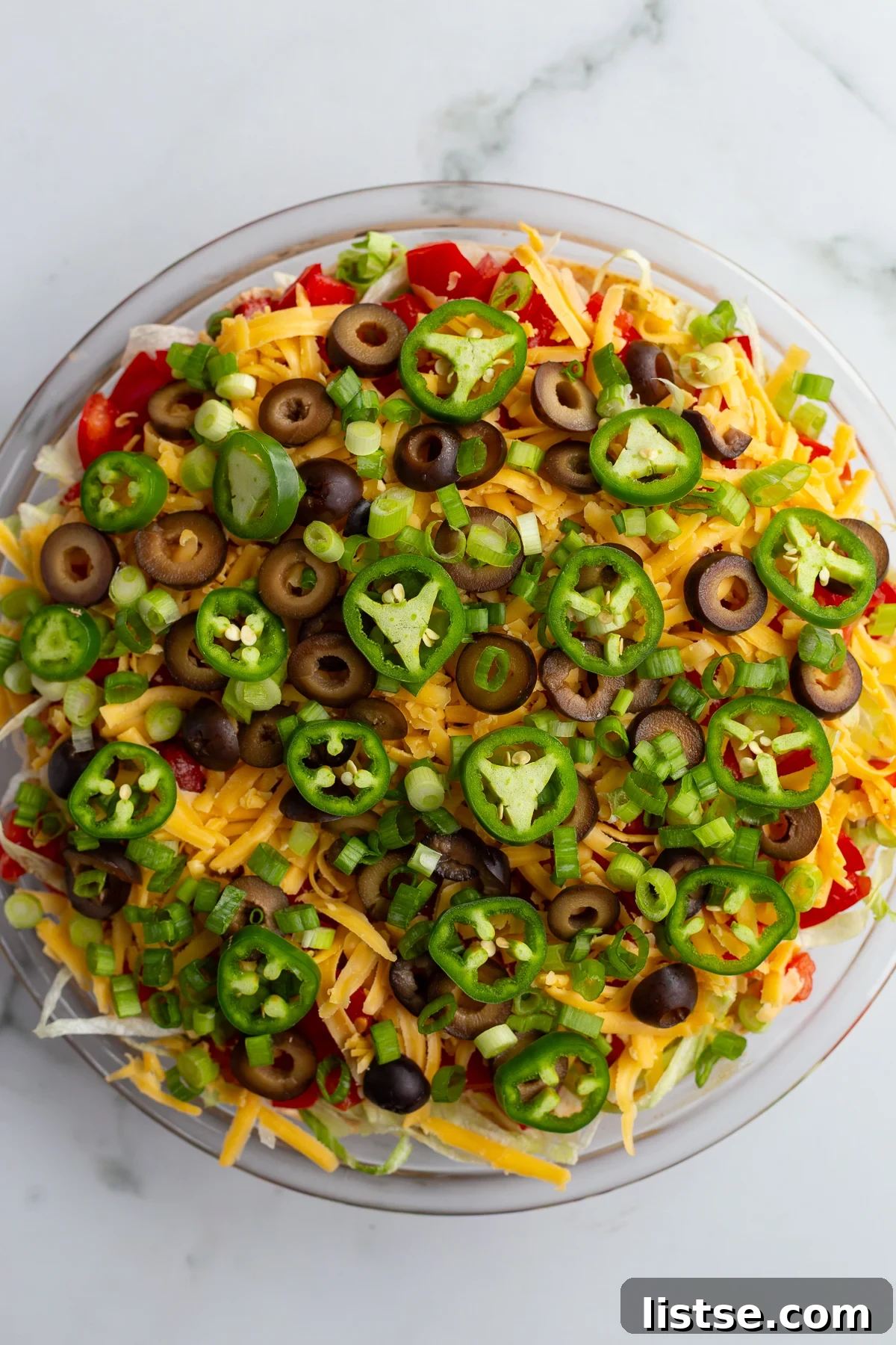Cream Cheese Taco Dip Recipe for Parties 2 taco dip with cream cheese that's layered like a 7 layer dip with beans, cream cheese, lettuce, cheese, jalapeno, olives, and tomato