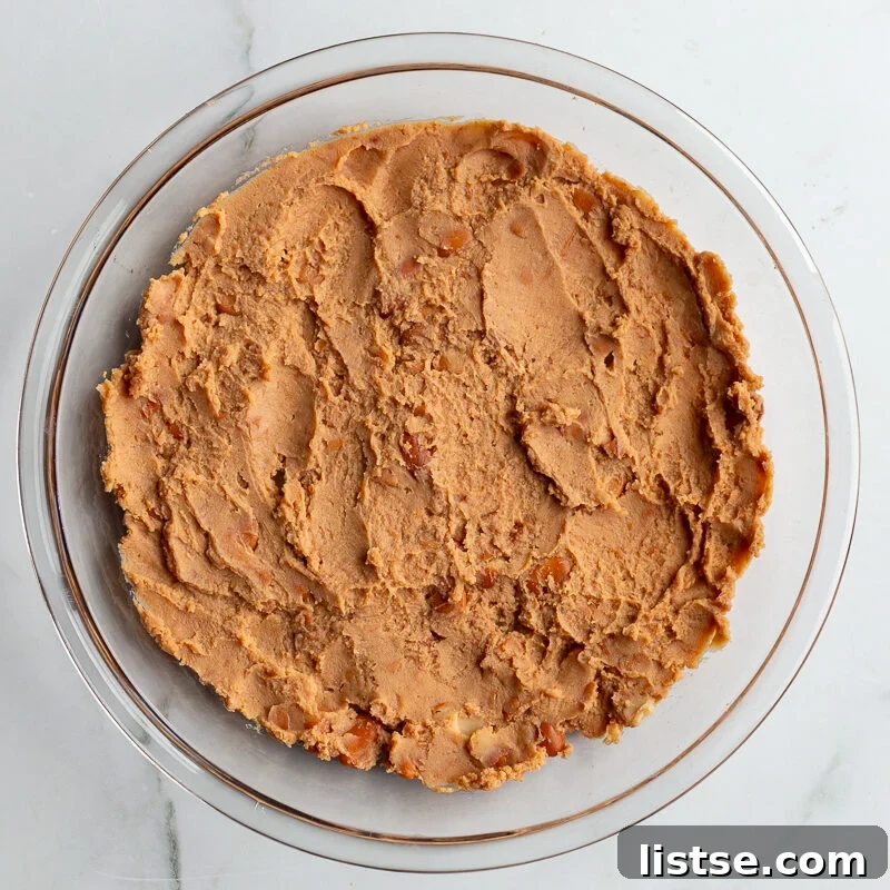 Cream Cheese Taco Dip Recipe for Parties 7 refried beans smeared in the bottom of a glass pie dish